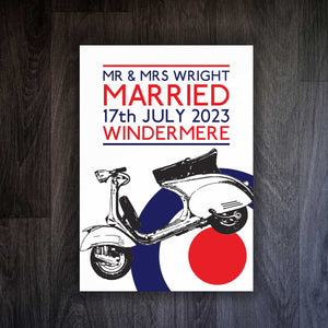 A white framed print featuring a Mod-inspired Targets and Scooters wedding design with a captivating London tube-style font. The retro-chic artwork showcases a playful and sophisticated motif, adding a touch of nostalgic charm to any wedding venue. The white frame accentuates the print, lending a clean and modern aesthetic, making it a striking centerpiece for your special day